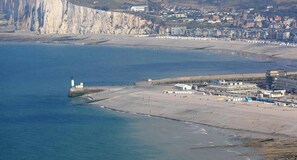 A coastal town with a prominent cliff, a lighthouse, and a beach area with buildings and a pier. - Villa marguerite charming bed and breakfast (Ponts-et-Marais)