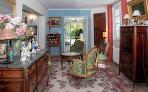 A room with a wooden dresser, a round table, and two chairs with floral upholstery. - Villa marguerite charming bed and breakfast (Ponts-et-Marais)