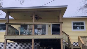 Una casa de dos pisos con balcón y ventilador de techo.
