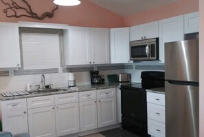 Kitchen features a microwave, black stove, and coffee maker.