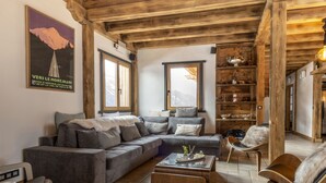 Una sala de estar acogedora con techo de madera, un sofá grande, una mesa de centro y una estantería.