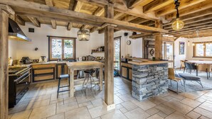 Una cocina amplia con una isla central, vigas de madera y una pared de acento de piedra.