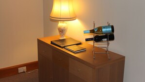 Una scrivania in legno con una lampada, una bottiglia di vino e un quaderno.
