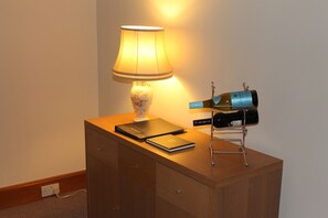 Un escritorio de madera con una lámpara, una botella de vino y una libreta.