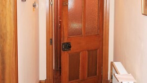Un corridoio con una porta in legno, un termosifone e quadri appesi alle pareti.