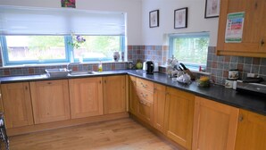 A kitchen with wooden cabinets, a black countertop, and a window with blinds.