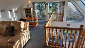A cozy living room with a sofa, a wooden table, and a staircase leading to a balcony.
