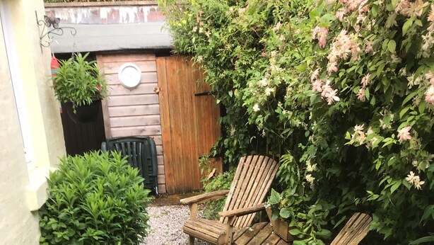 Un jardin avec deux fauteuils Adirondack en bois, une clôture en bois et diverses plantes.