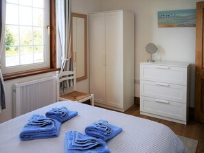 A bedroom with a bed, a wardrobe, a radiator, a window, and a painting on the wall. - Primrose Cottage -  a cottage that sleeps 4 guests  in 2 bedrooms (Rockcliffe)
