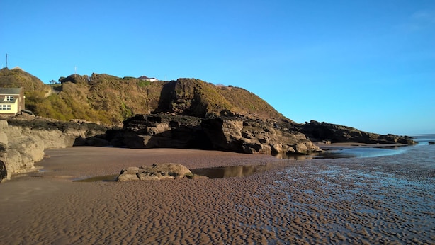 A coastal landscape with a rocky shoreline, a sandy beach, and a building on a cliff. - Portling View -  an apartment that sleeps 6 guests  in 3 bedrooms (Dalbeattie)