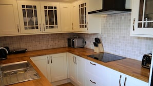 A kitchen with white cabinets, a wooden countertop, a built-in microwave, and a toaster. - Portling View -  an apartment that sleeps 6 guests  in 3 bedrooms (Dalbeattie)