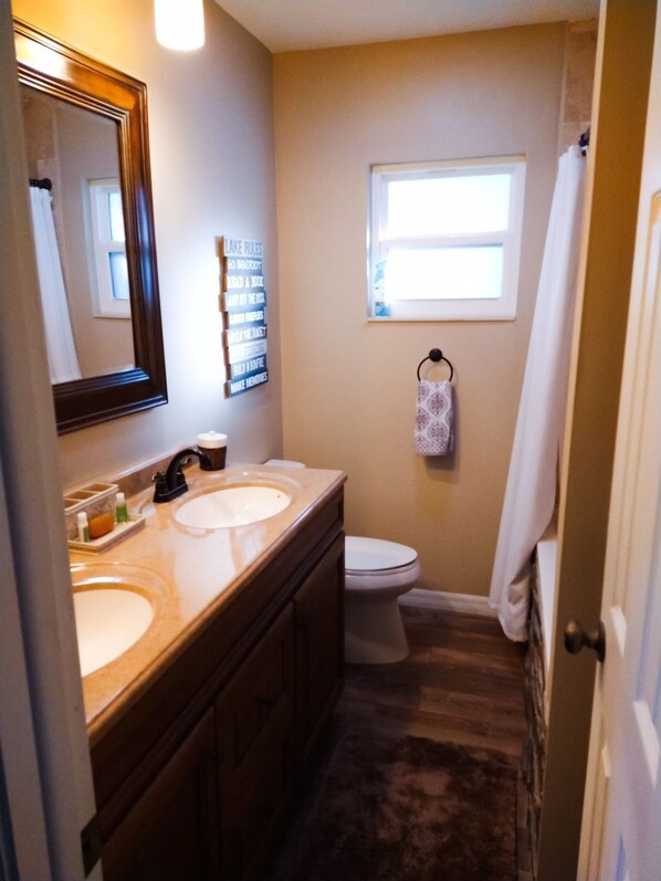 A bathroom with two sinks, a toilet, a towel rack, and a window. - Lake Front, Pool Home with Boat Dock (Inverness)