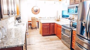Een moderne keuken met houten kastjes, granieten aanrechtbladen, roestvrijstalen apparatuur en een centraal eiland.