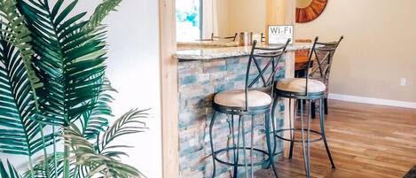 A modern kitchen with wooden beams, a stone backsplash, and a bar area.