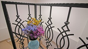 A metal railing with a vase of flowers. - Narlı Pansiyon (Bozcaada)