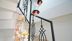 A staircase with a decorative hanging ornament featuring seashells and a bell. - Narlı Pansiyon (Bozcaada)