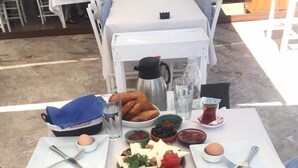 A table set for a meal with various dishes including bread, cheese, nuts, and watermelon. - Narlı Pansiyon (Bozcaada)
