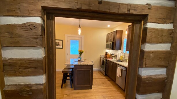 A kitchen with wooden walls, a central island, and a dining area with stools.