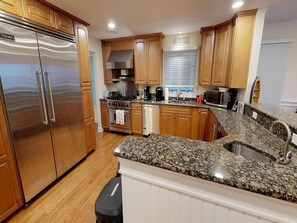 Enjoy cooking in this well-equipped kitchen with a granite countertop, sink, and range hood.