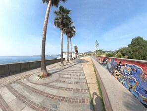 Eine Strandpromenade mit Palmen, gemustertem Pflaster und Wandmalerei.