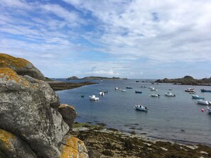 A coastal scene with rocky shores and calm waters. - the house of the end of the world (Porspoder)