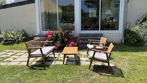 A conservatory with a glass door, a wooden table, and two chairs in a garden. - the house of the end of the world (Porspoder)