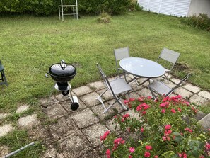 A patio with a grill, a table, and chairs. - the house of the end of the world (Porspoder)