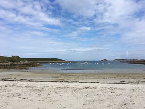 A beach with boats in the water and rocky hills in the background. - the house of the end of the world (Porspoder)