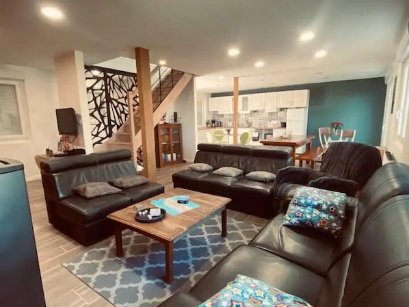 A modern living room with two sofas, a coffee table, and a staircase leading to a kitchen.