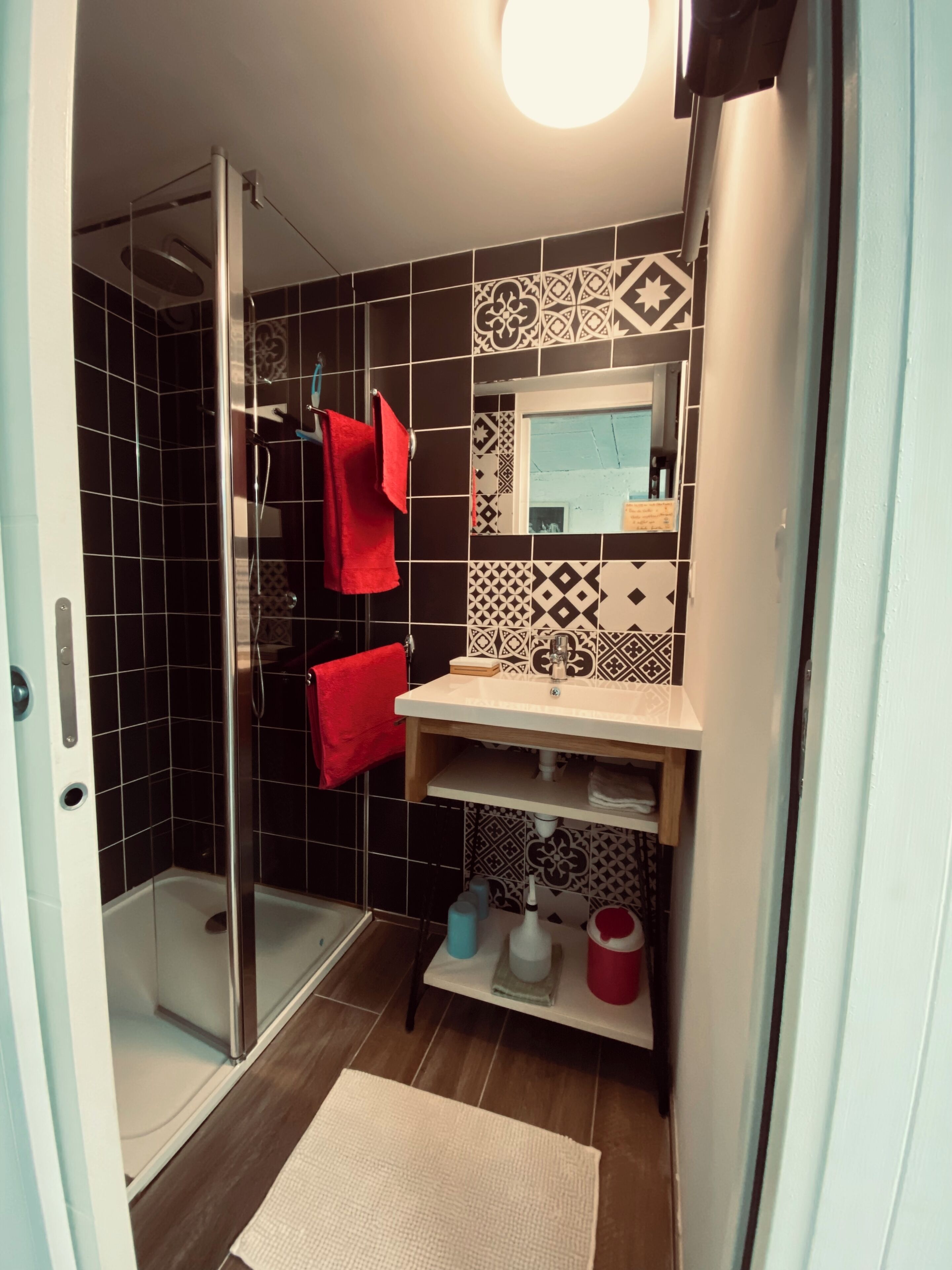 Un baño con cabina de ducha de vidrio, un lavabo con espejo y un salpicadero de azulejos.