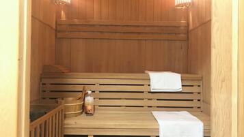 A sauna with wooden benches and benches, a bottle of lotion, and towels.