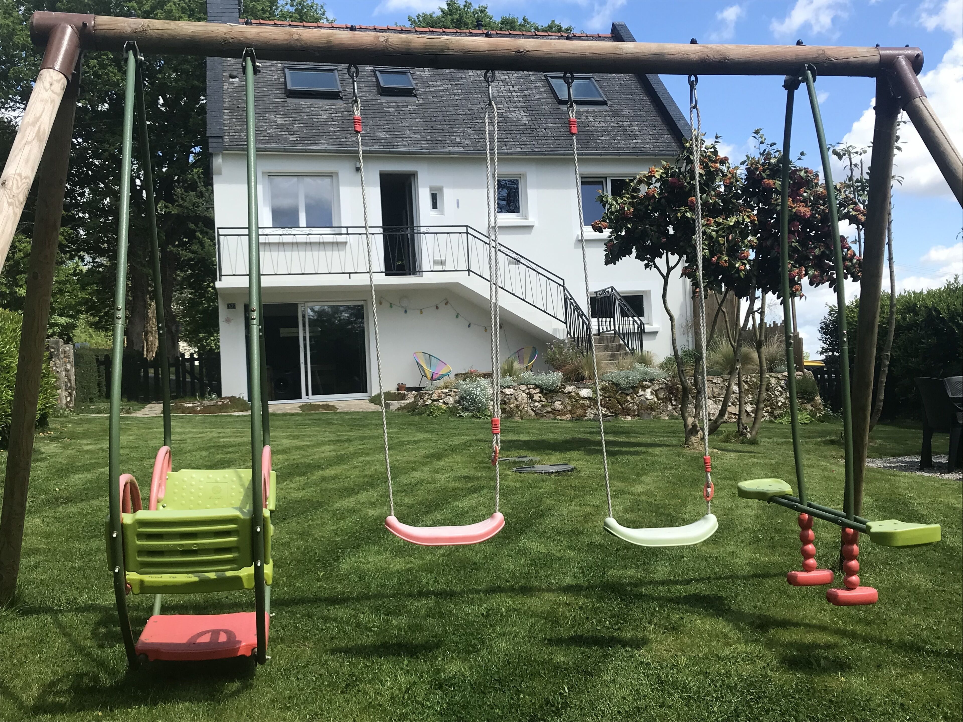 A swing set in a backyard with a house in the background.