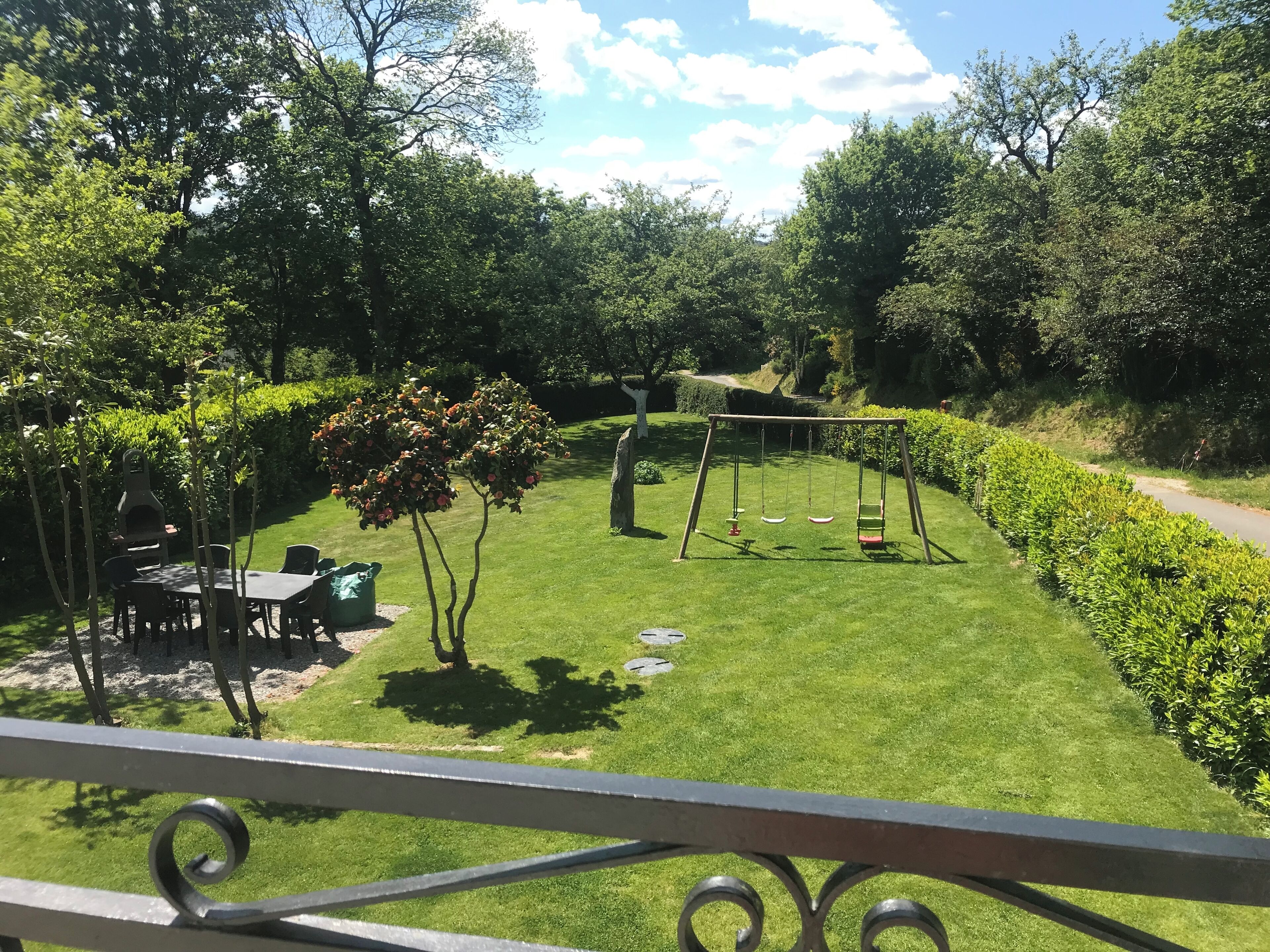 Ein gepflegter Garten mit Schaukel, Grillplatz und ordentlich geschnittenen Hecken.