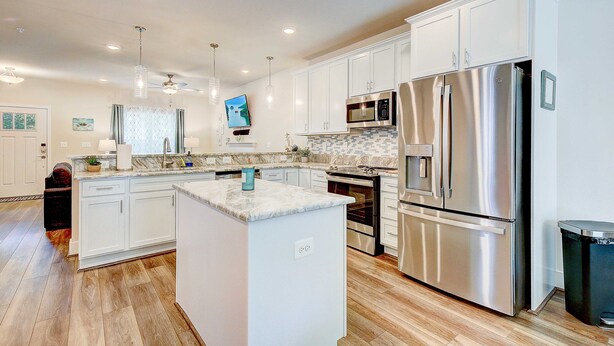 A modern kitchen with white cabinets, stainless steel appliances, and a marble countertop. - Harbor Breezes at Herrington Harbor (North Beach)