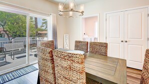 A dining area with a wooden table and woven chairs, a chandelier, and a view of the outdoors. - Harbor Breezes at Herrington Harbor (North Beach)