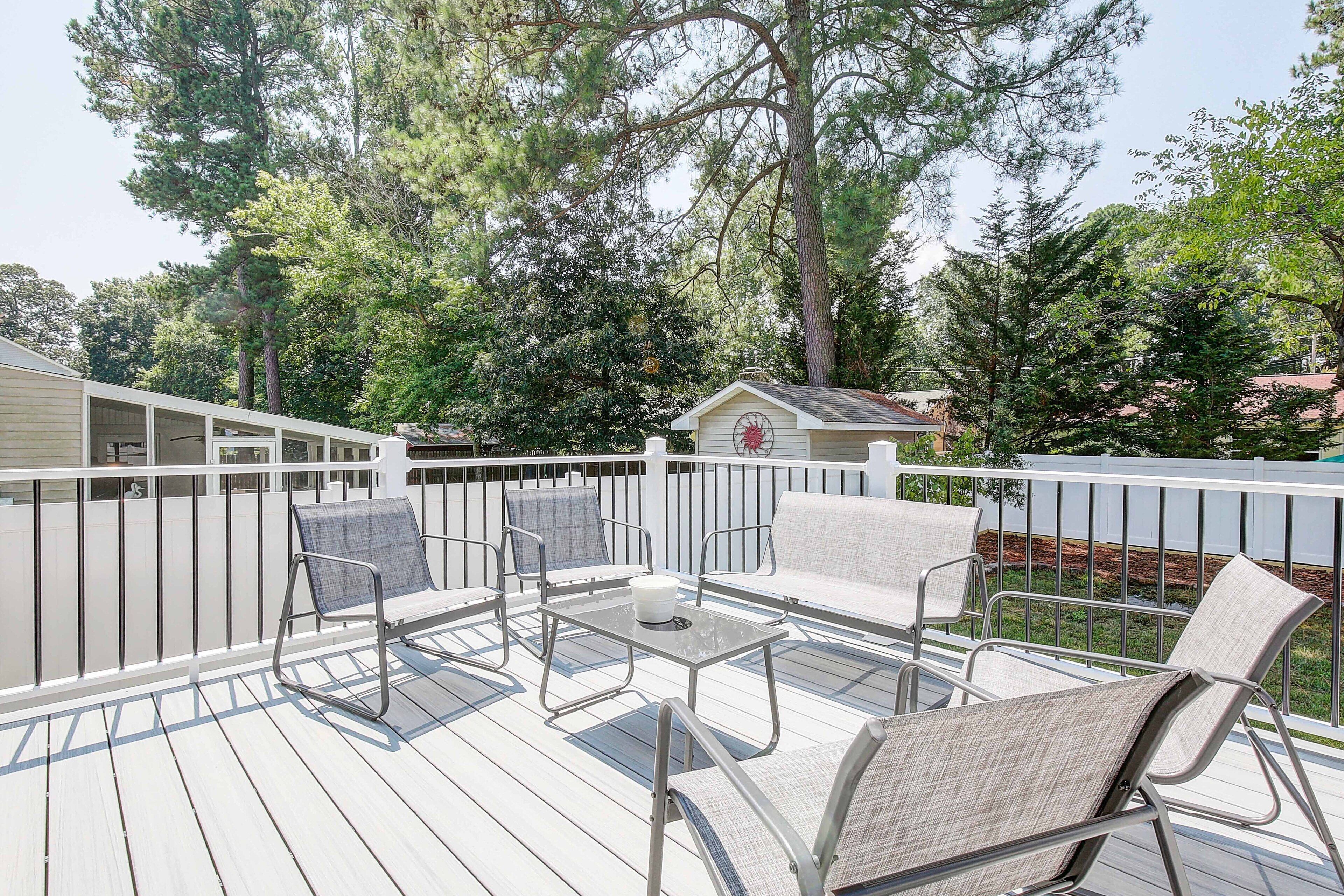 Eine Terrasse mit Gartenmöbeln, darunter Stühle und ein Tisch, umgeben von einem weißen Geländer.
