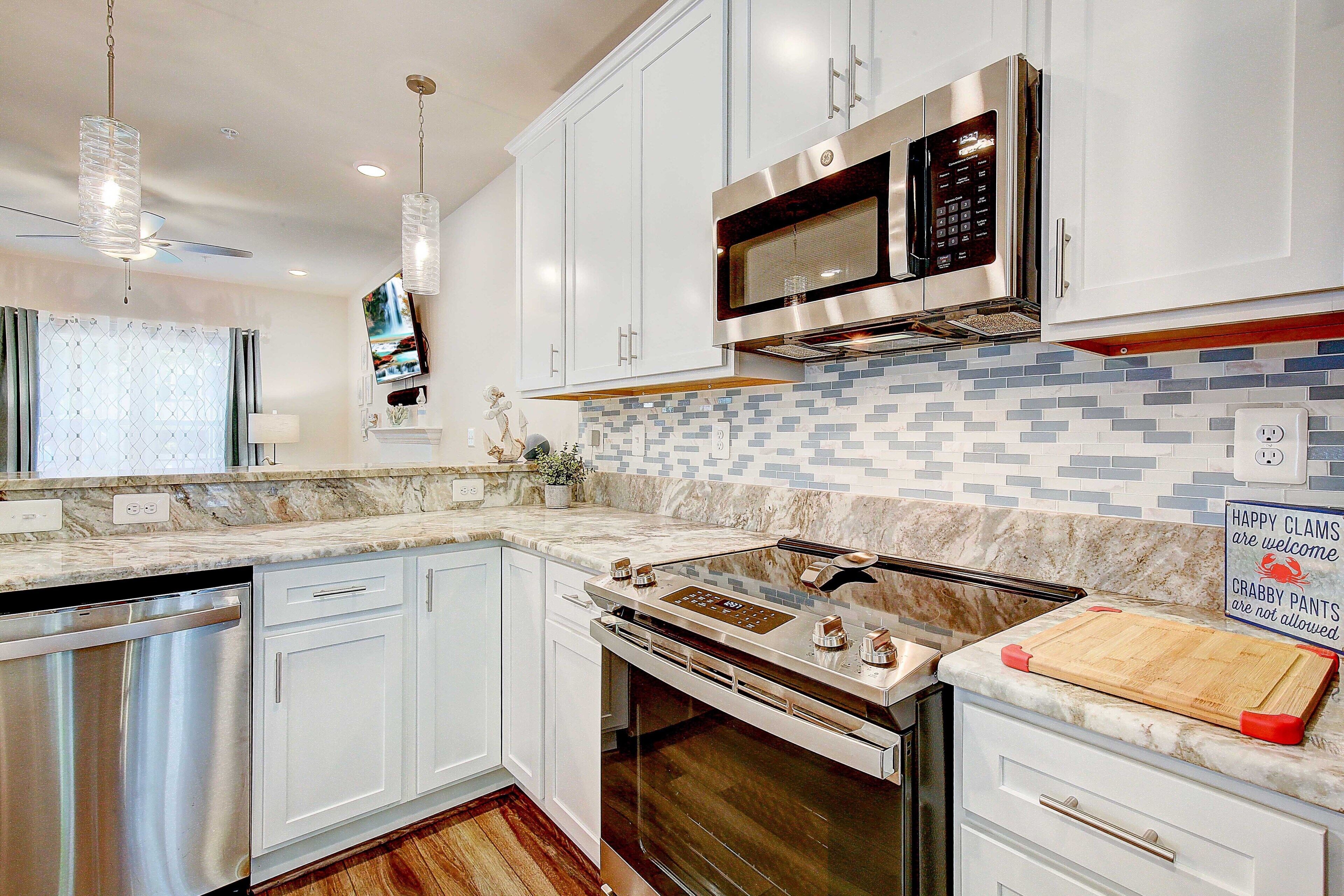 A modern kitchen with white cabinetry, a stainless steel range, a microwave, and a tiled backsplash.