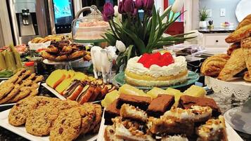 A kitchen counter with various baked goods, a cake with a strawberry on top, and a decorative cow figurine.