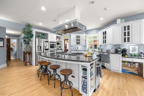 A modern kitchen with white cabinetry, a granite countertop, and a central island with stools.