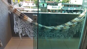 Una hamaca colgada en un balcón con vista a una calle y edificios.