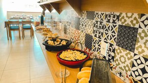 A buffet setup with various food items and a patterned wall. - Pousada São Pedro (Sao Pedro da Aldeia)