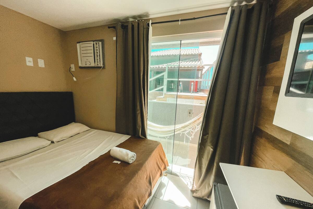 A hotel room with a bed, a desk, and a window with curtains.