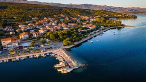 Un pueblo costero con un puerto deportivo, casas y montañas al fondo.