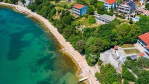Vista aérea de una zona residencial costera con casas, una playa y aguas turquesas cristalinas.