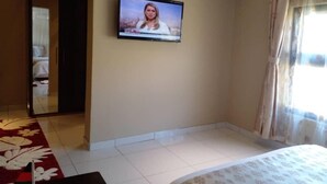 A hotel room with a bed, a television mounted on the wall, and a window with curtains. - Chikho Hotel Mponela (Mponela)