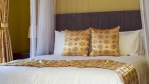 A neatly made bed with a canopy, two decorative pillows, and a bedspread. - Chikho Hotel Mponela (Mponela)