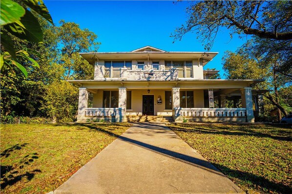 A two-story building with a central entrance, columns, and a covered porch.