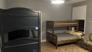 Cozy bedroom with a bunk bed arrangement, featuring a comfortable mattress and pillows, a bedside table, and a patterned rug.