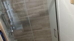 Uma casa de banho moderna com cabine de duche em vidro, sanita e lavatório.
