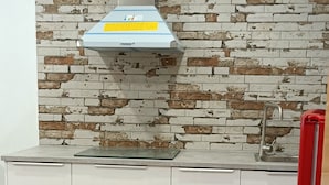 Cozinha com armários brancos, painel de backsplash em padrão tijolo e coifa de aço inoxidável.